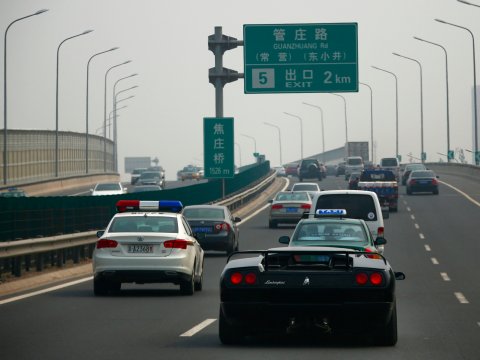 Una replica artigianale cinese di Lamborghini Diablo accanto a una macchina della polizia, a sinistra, nel corso di un test drive a Pechino, 21 agosto 2014