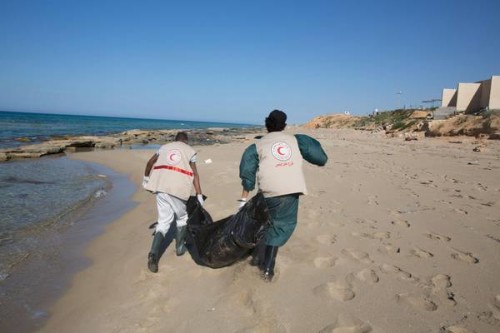 Alcuni operatori della Mezzaluna Rossa libica mentre stanno recuperando i corpi dei migranti annegati estraendoli direttamente da sotto la sabbia (quasi fossero immondizia), sulla spiaggia della Gasr Garabulli, ad est della città di Tripoli, in Libia, il 29 marzo 2016.